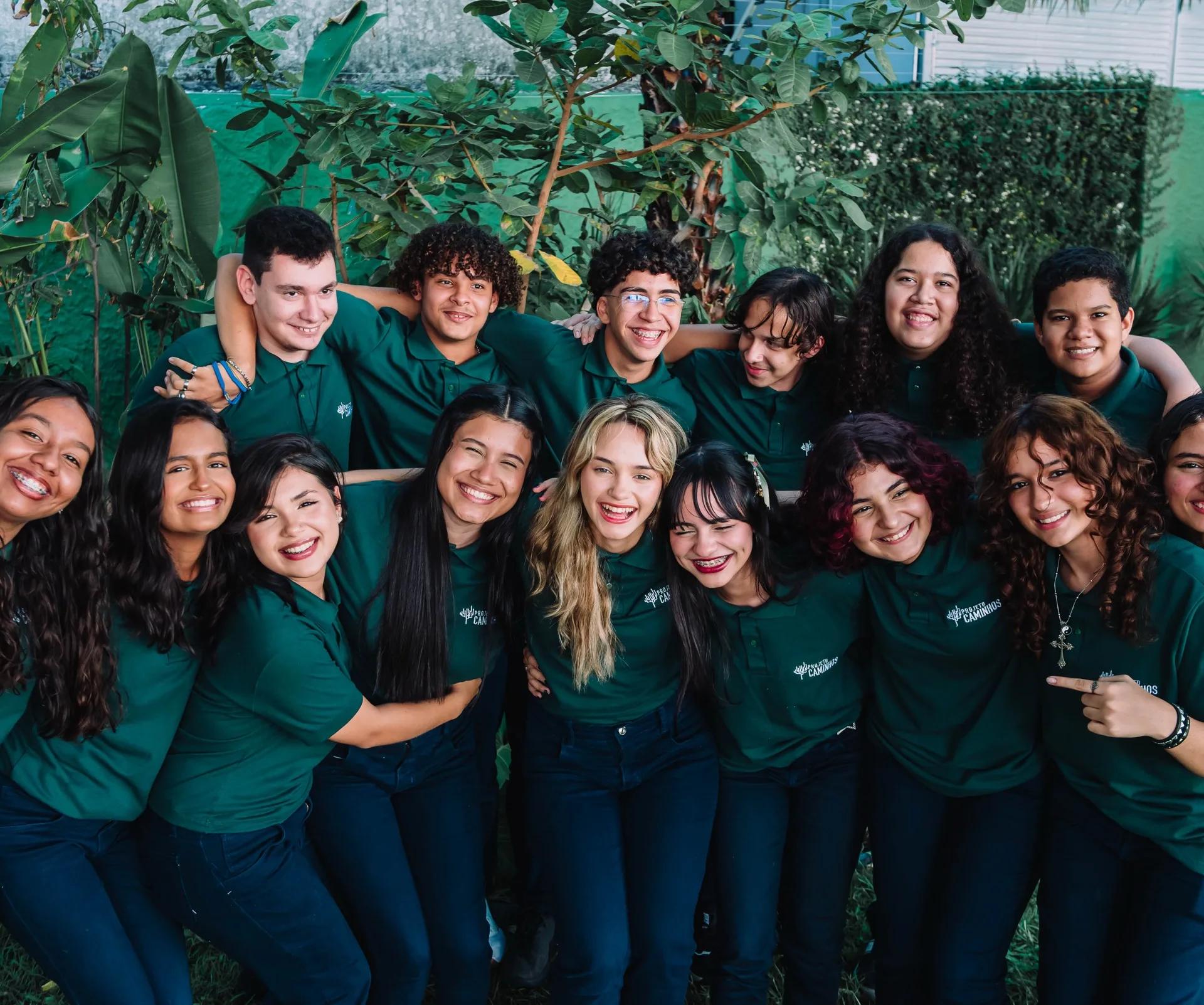 Bolsistas do Projeto Caminhos reunidos e sorrindo, de camisa verde do projeto